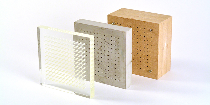 Samples of perforated breathing wall panels made of acrylic, concrete, and wood