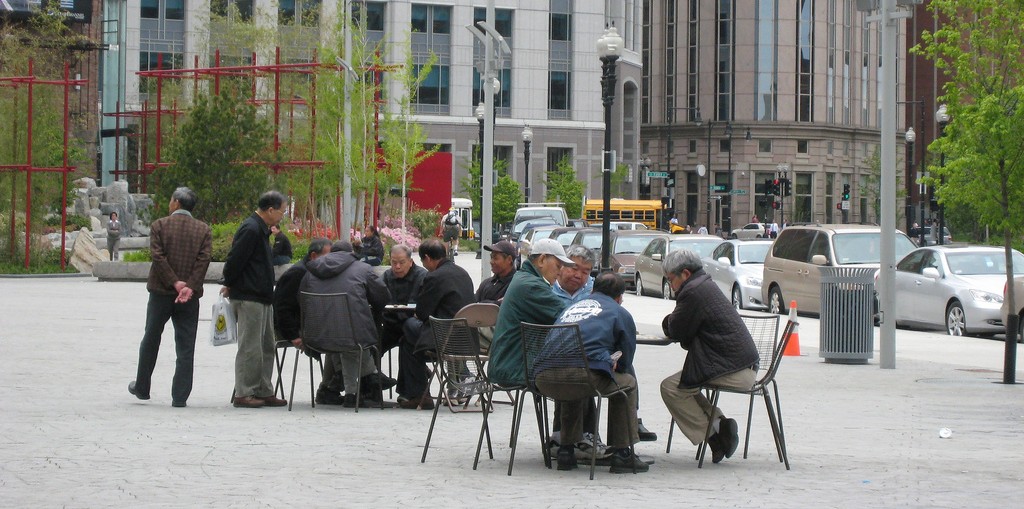 Older adults, chatting at outdoor tables. 