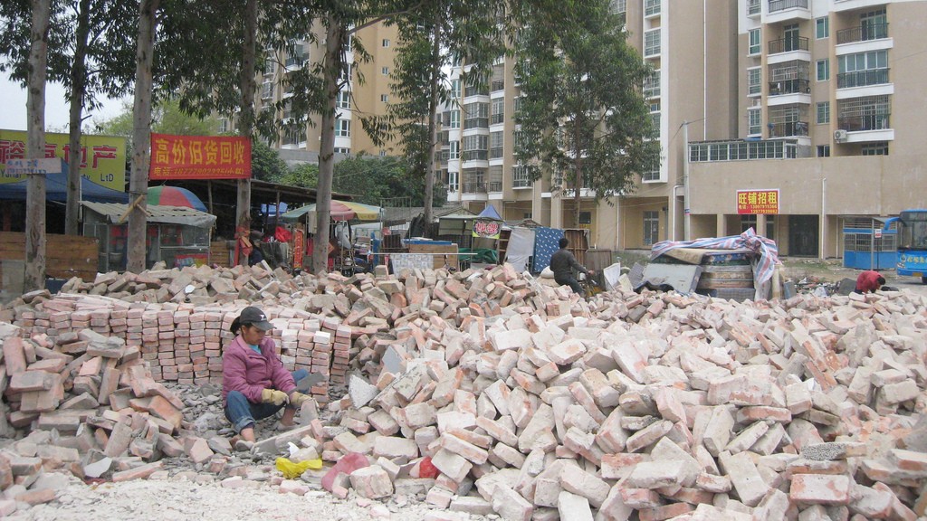 Woman surrounded by scattered red bricks.