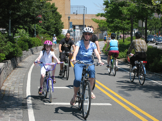 Several people biking in both directions along separated bike path. 