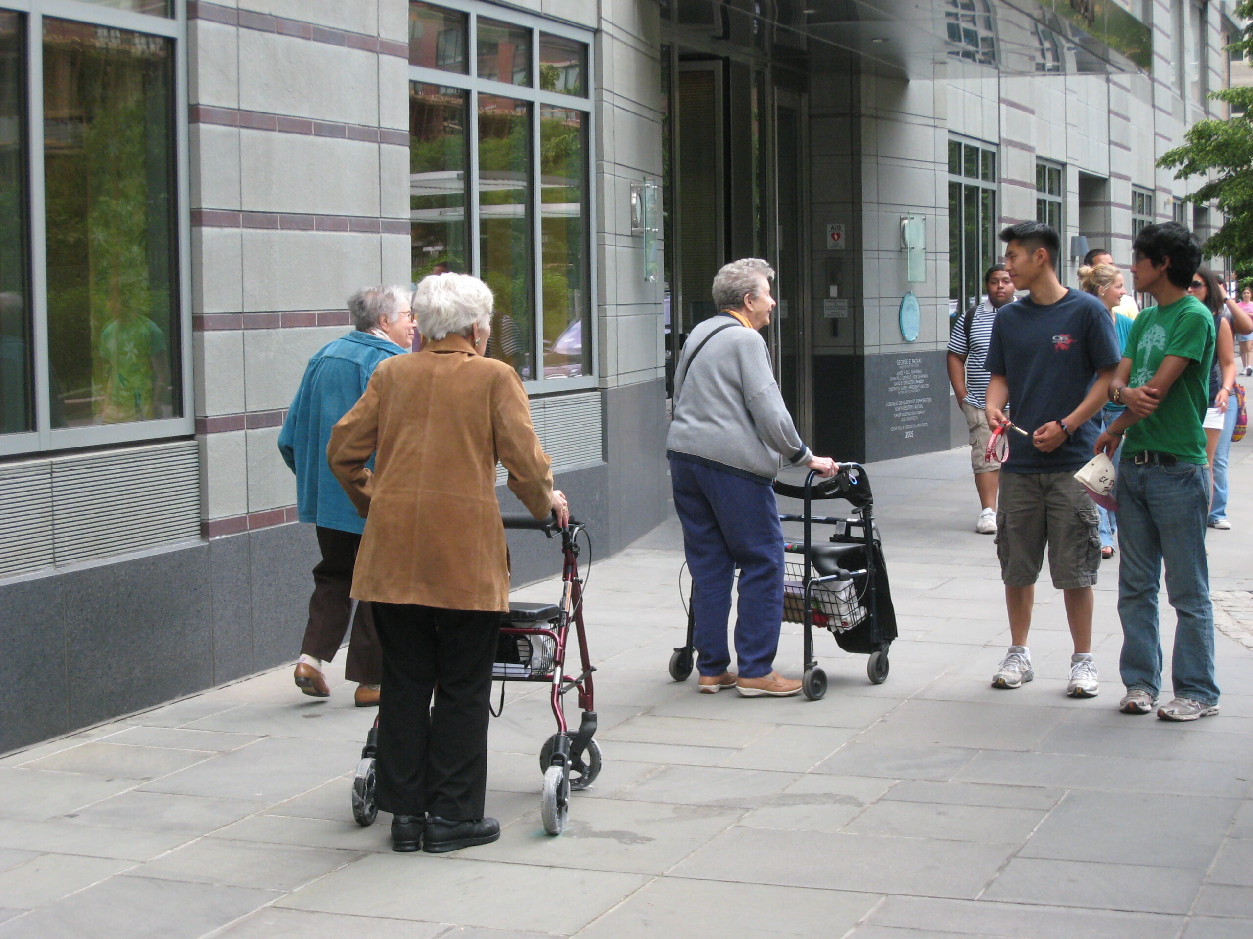 Older adults chat with younger people on sidewalk.