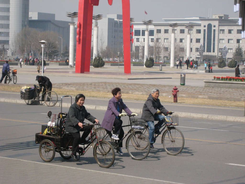 Three people ride bicycles on a road.