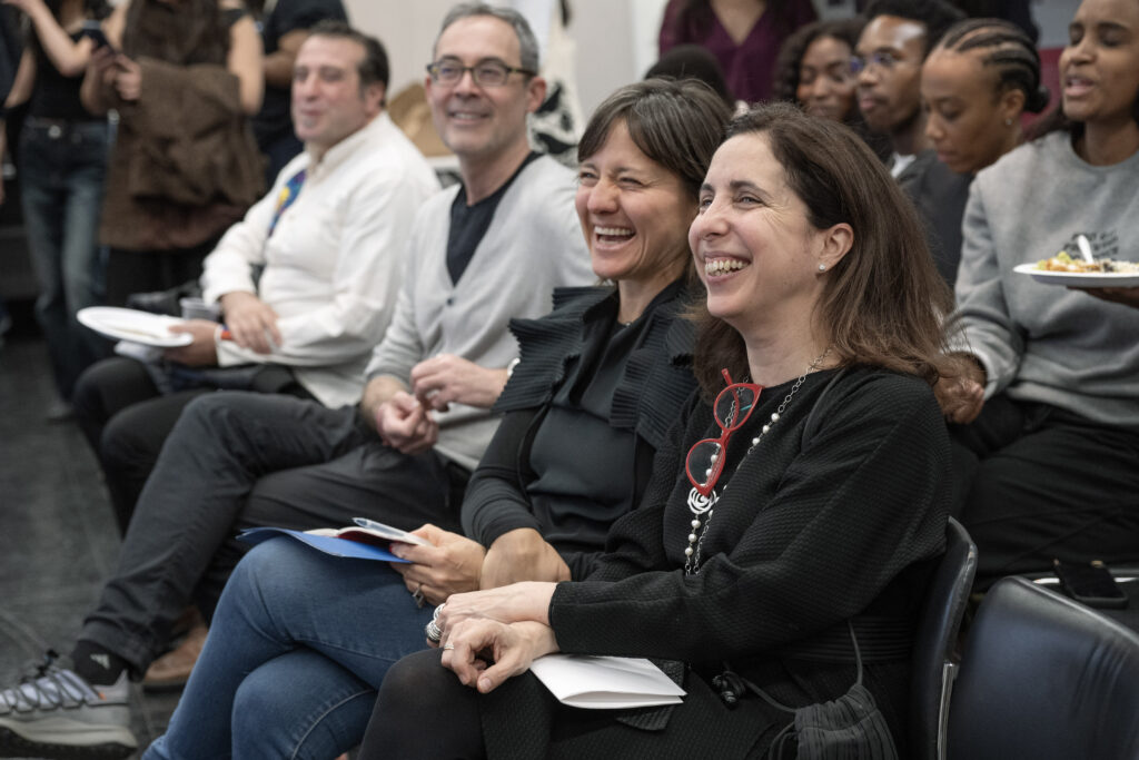 Audience members smiling and applauding during a symposium session
