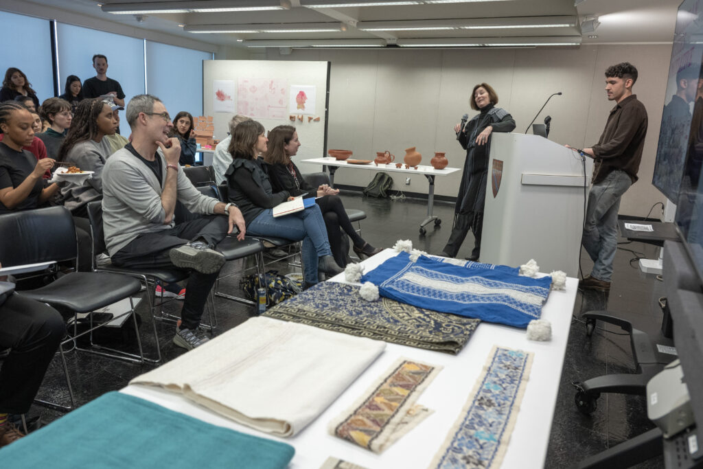 Attendees seated at a table examining archival textile and paper materials during a presentation