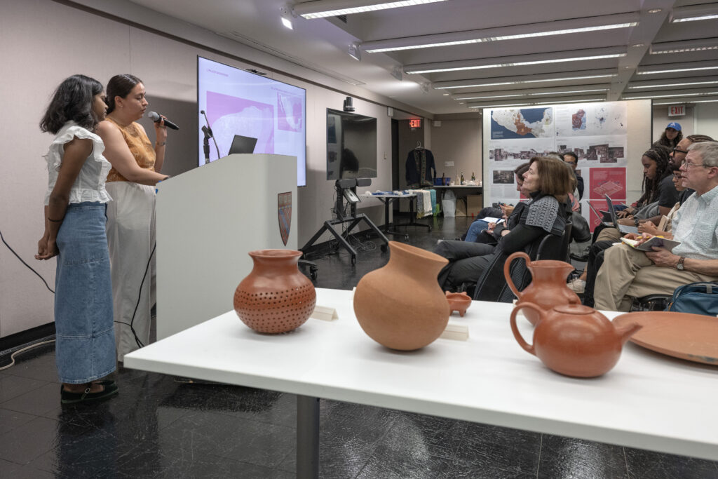 Ceramic vessels displayed on a table with a presentation screen in the background