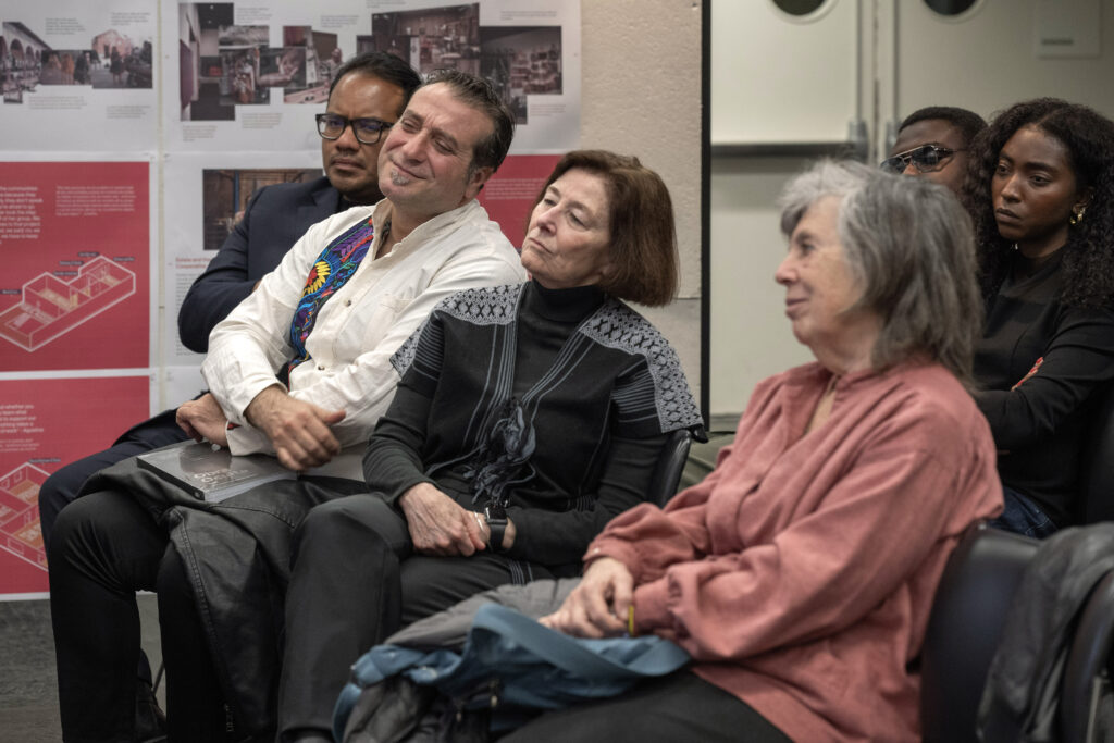Panelists seated together smiling, with an event banner in the background"