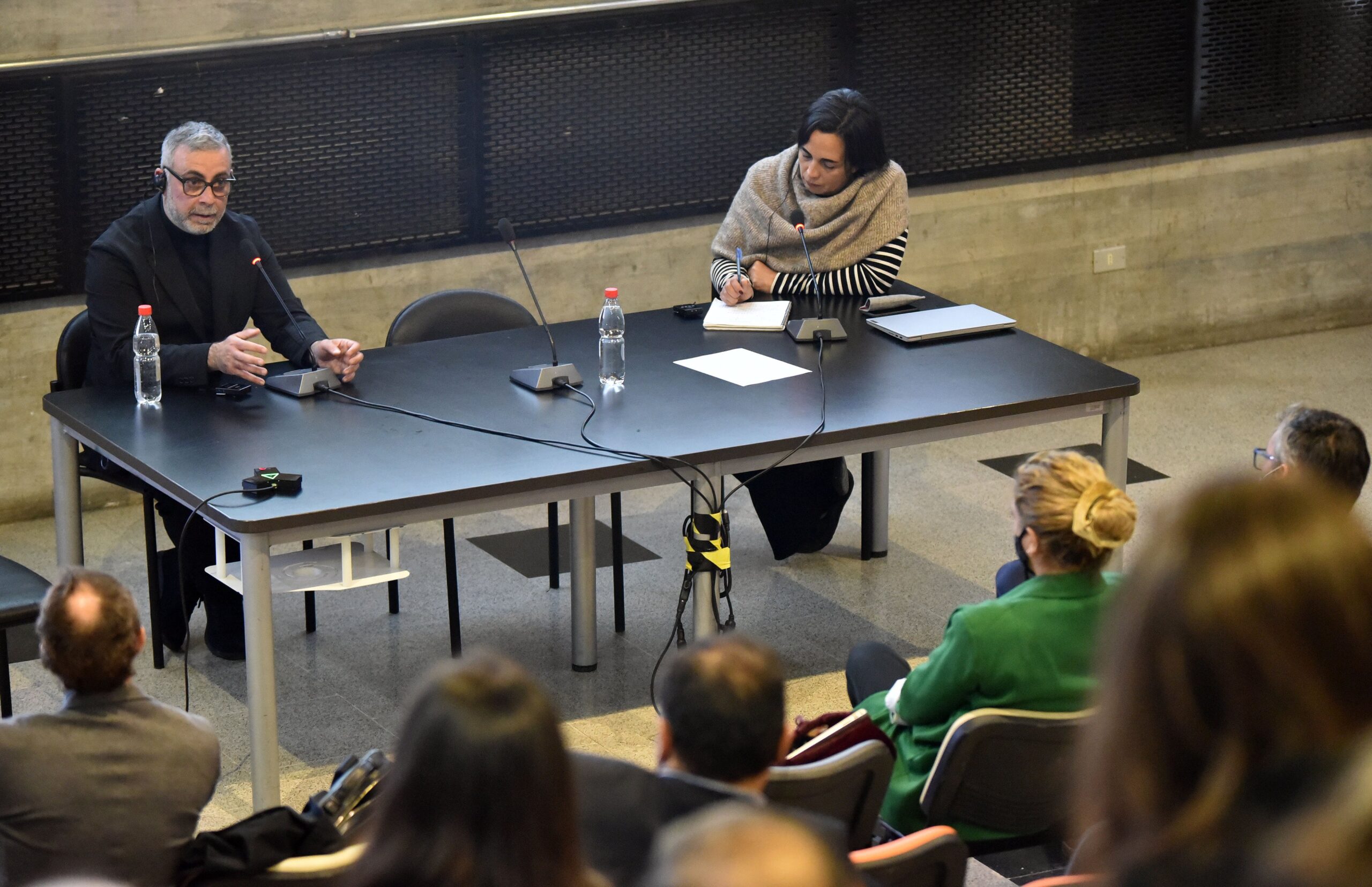 Two presenters talking around a black table