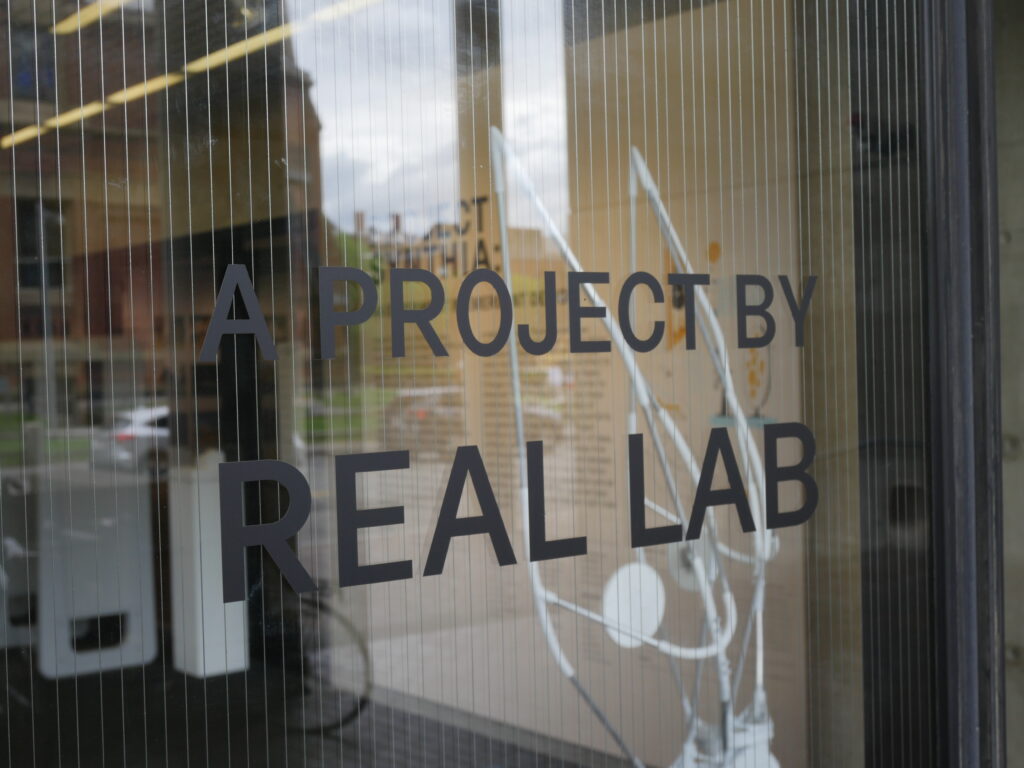 Text on glass "A project by REAL lab"