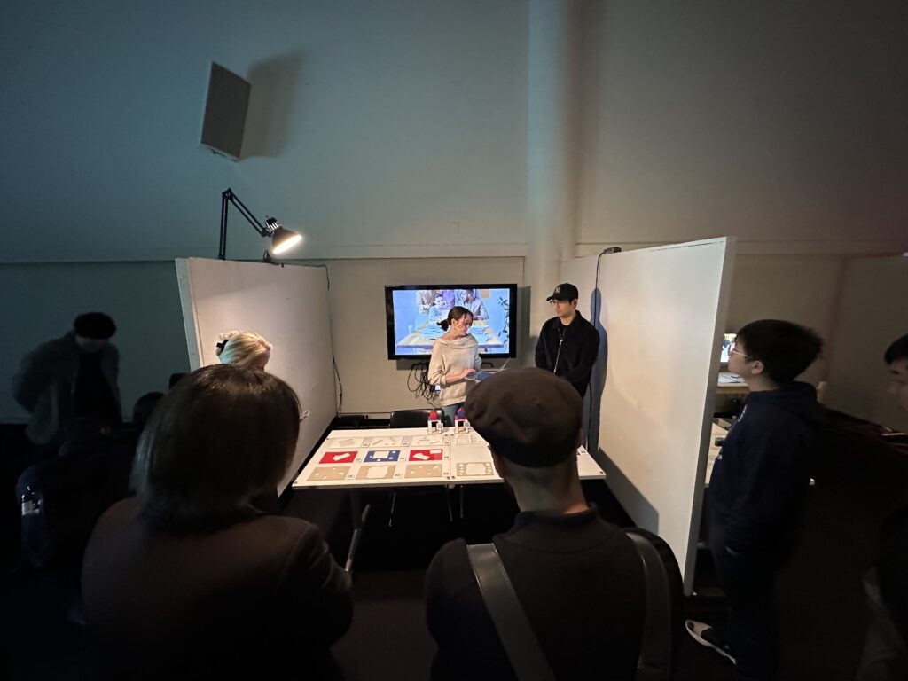 Two students standing infront of a table.