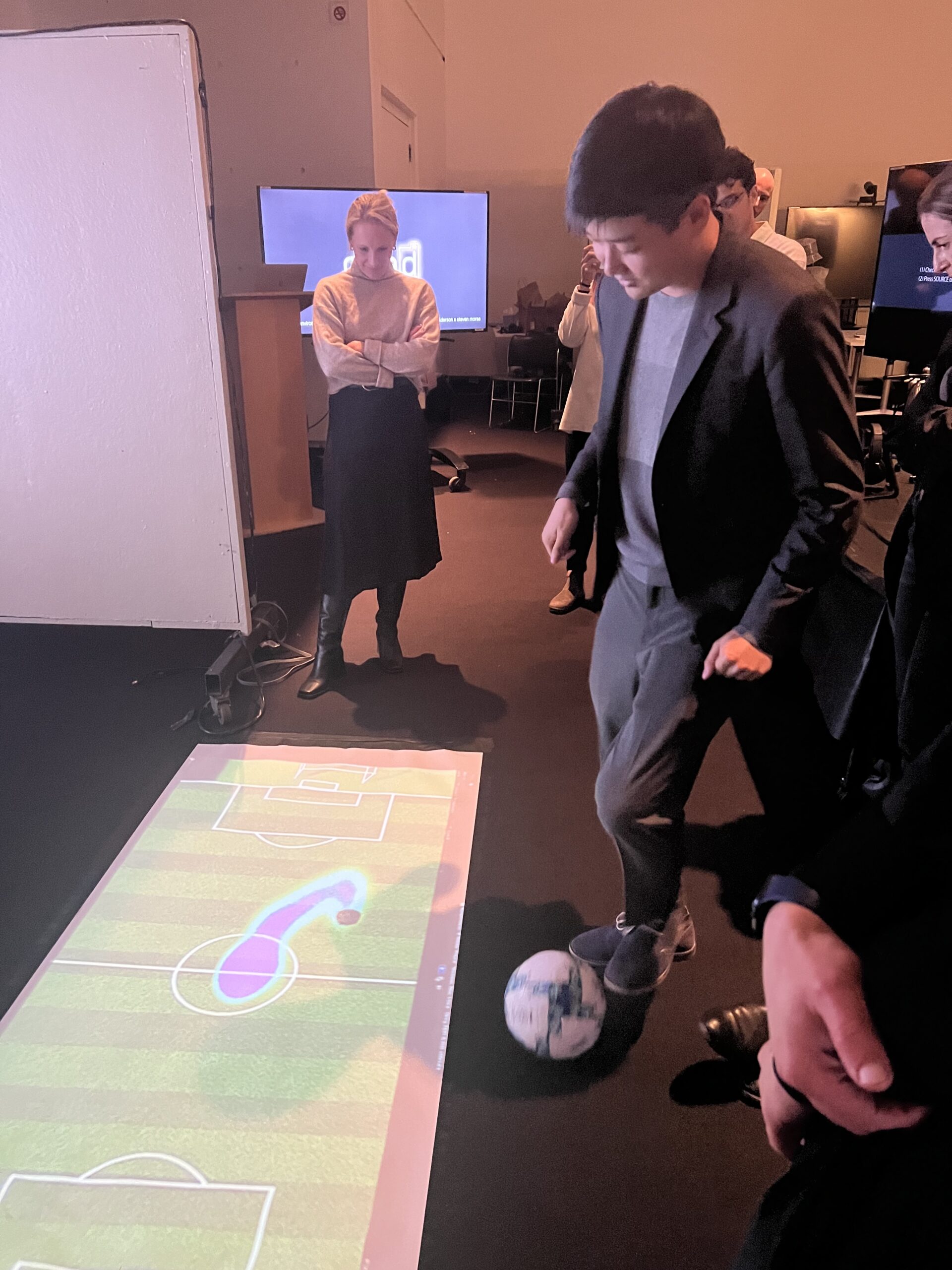 Studnet playing football on floor projection.